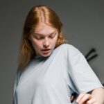 A startled young woman looks at a cockroach on her shirt indoors, conveying fear.