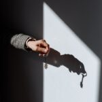 Hand with a key casting a dramatic shadow on a wall, symbolizing property or ownership.