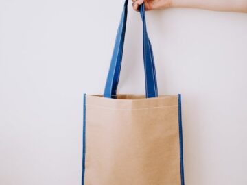Hand holding a reusable bag with blue handles, showcasing eco-friendly living.