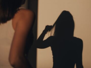 A woman indoors with her silhouette casting a dramatic shadow on the wall.
