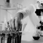 Focused scientist working with microscope and test samples in lab.