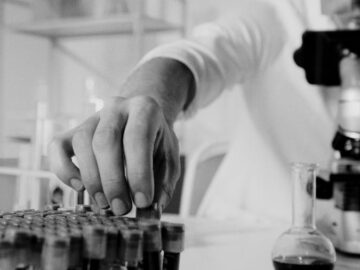 Focused scientist working with microscope and test samples in lab.