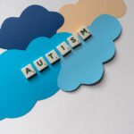 Creative depiction of autism awareness using Scrabble tiles and paper clouds in a flat lay style.