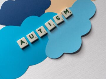 Creative depiction of autism awareness using Scrabble tiles and paper clouds in a flat lay style.