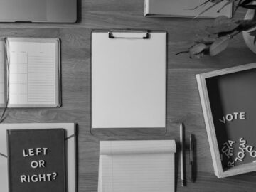 Top view of a desk with voting-themed items, including a notepad with 'Left or Right?' and scattered letters spelling 'Vote'.