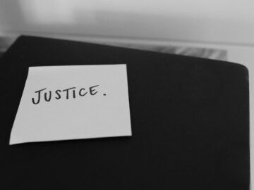 Black and white photo of a sticky note with 'Justice' written on it, conveying a powerful message.