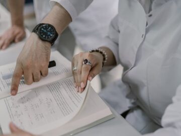 Two scientists examine a research document in a lab setting, pointing at complex equations.