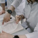 Two scientists examine a research document in a lab setting, pointing at complex equations.