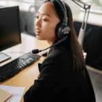 Asian woman using headset for customer support in a modern office.