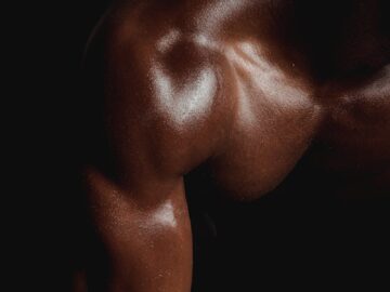 Close-up of a well-defined muscular arm, highlighting fitness and strength in low light.