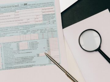 A detailed view of a tax return form with a pen and magnifying glass, perfect for financial themes.