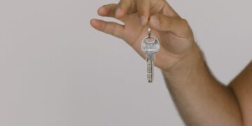 Close-up of two hands exchanging a key, symbolizing a real estate transaction.