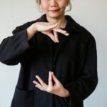 A woman in a studio using sign language against a white background.