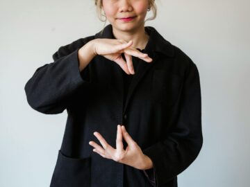 A woman in a studio using sign language against a white background.