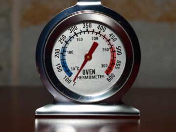 Close-up of a metallic oven thermometer showing temperature in Celsius and Fahrenheit.