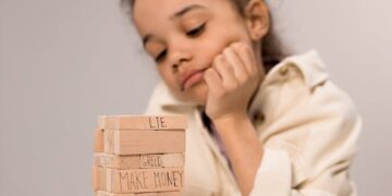 A young girl contemplates a stack of wooden blocks with words like 'lie' and 'kindness.'