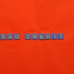 Blue letter blocks spelling 'Bad Credit' on an orange background.