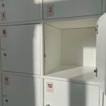 White storage locker with open door and numbered labels in soft daylight.