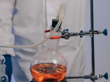 Scientist conducting experiment using laboratory glassware and chemicals.