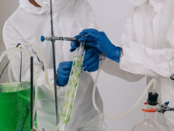 Two scientists in protective gear conducting an experiment in a laboratory setting.