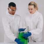 Two scientists in protective gear conducting an experiment with a green chemical solution in a laboratory.