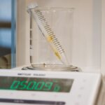 Close-up of lab equipment featuring a beaker, sample tube, and digital scale for precise weighing.