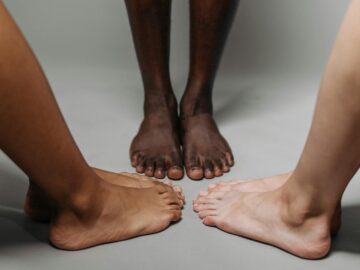 Close-up of diverse adult feet on a neutral background symbolizing unity.