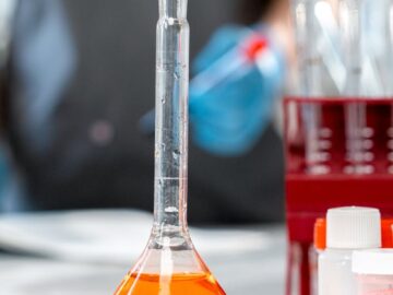 A close-up shot of a laboratory flask with orange liquid, highlighting scientific research equipment.