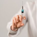 Detailed image of a hand holding a vaccine syringe, highlighting healthcare and medicine concepts.