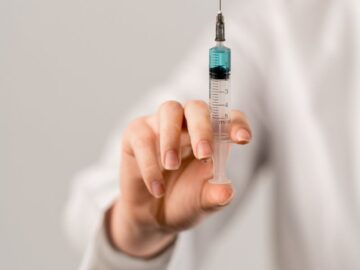 Detailed image of a hand holding a vaccine syringe, highlighting healthcare and medicine concepts.