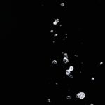 Close-up of water droplets captured mid-air against a stark black background, highlighting fluid motion and texture.