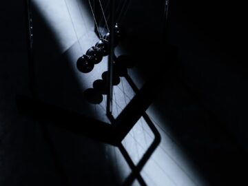A stark contrast image of Newton's cradle casting dramatic shadows in studio lighting.