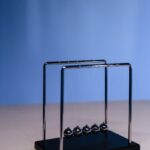 Studio shot of a Newton's cradle on a blue gradient background, illustrating physics concepts.