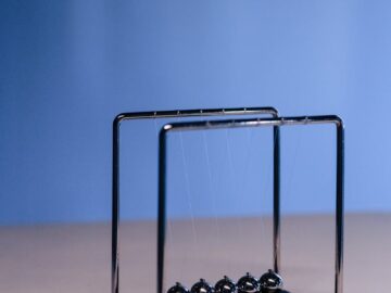 Studio shot of a Newton's cradle on a blue gradient background, illustrating physics concepts.