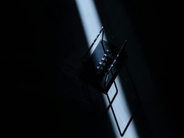 Newton's cradle in a dark room with striking light, showcasing physics concepts.