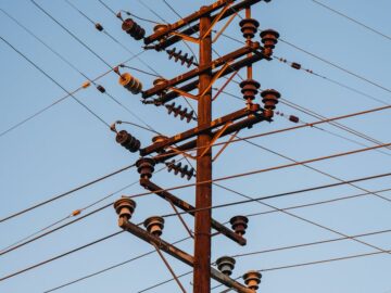 Close-up of a high voltage utility pole with transmission lines against a clear blue sky.