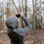 man in gray sweater holding black camera