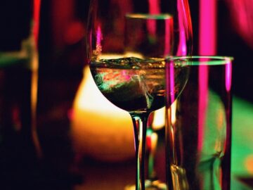 half filled wine glass beside half empty clear pint glass