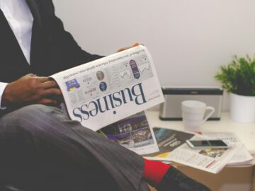 person sitting near table holding newspaper