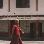 A monk walks in front of a building.