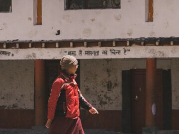 A monk walks in front of a building.