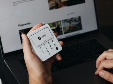 A person holding a cell phone in front of a laptop